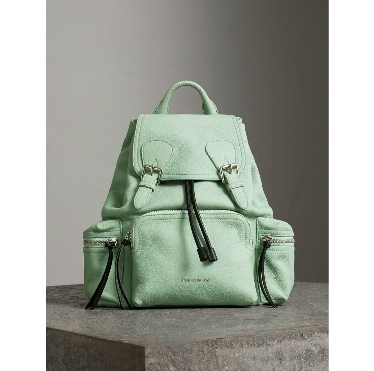 A light green backpack sitting on top of a concrete surface.