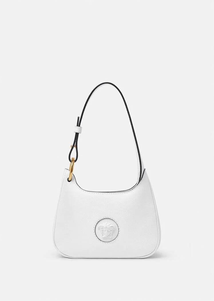 A white purse with a black strap and a gold charm.