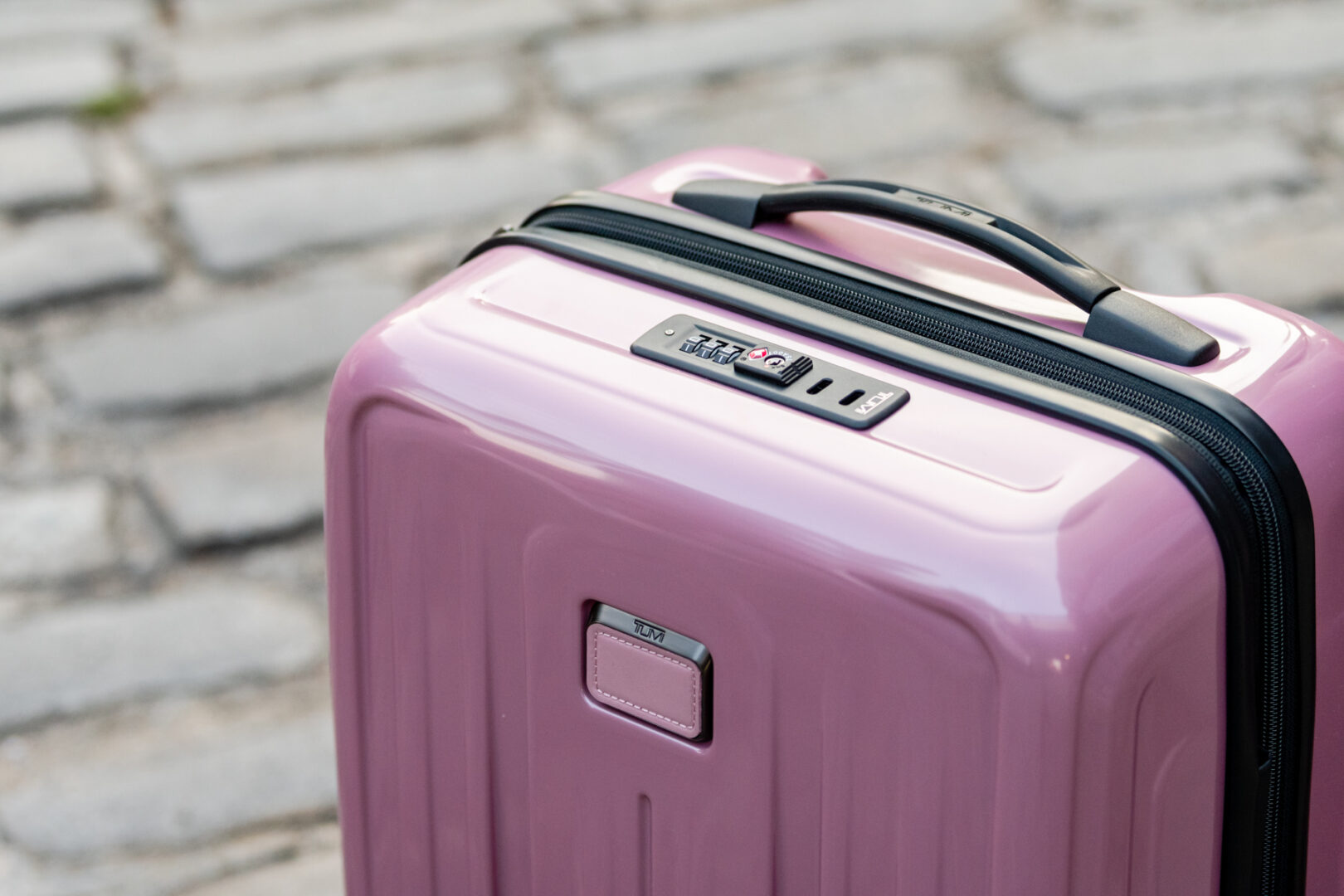 A pink suitcase is sitting on the ground.