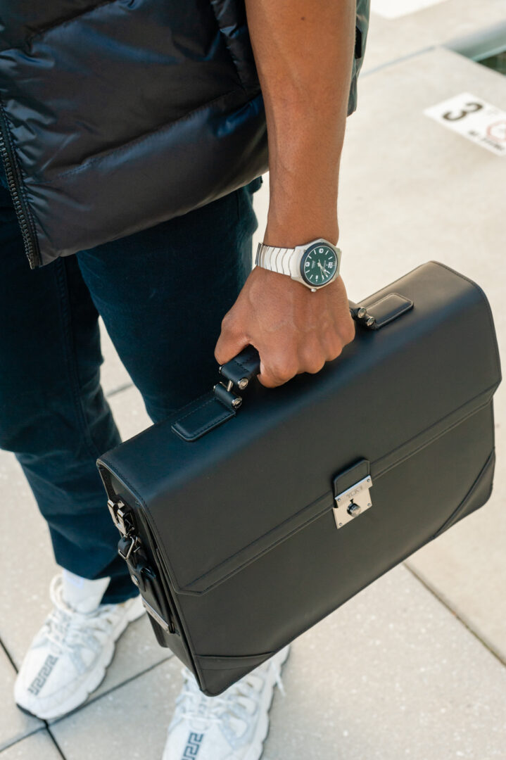 A man holding his briefcase and wearing a watch.