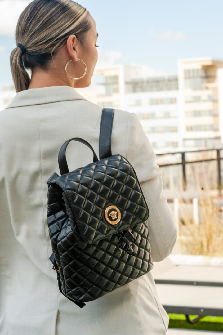 A woman wearing large hoop earrings and carrying a black backpack.