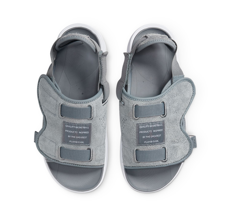 A pair of gray sandals on top of white background.