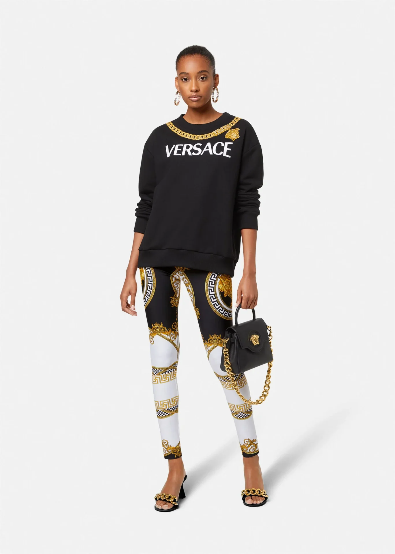 A woman in versace leggings and black sweatshirt.