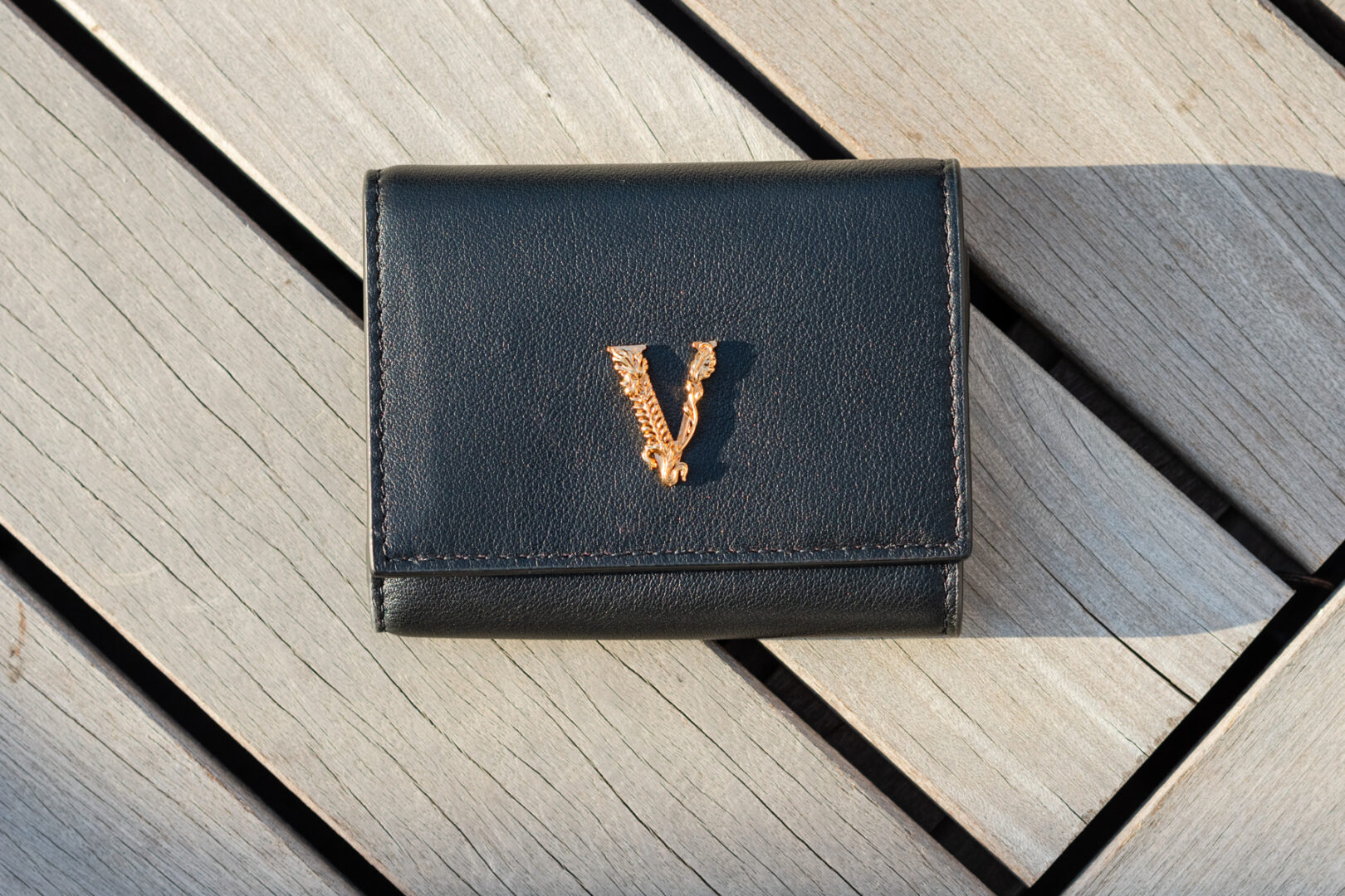 A black wallet with the letter v on it.