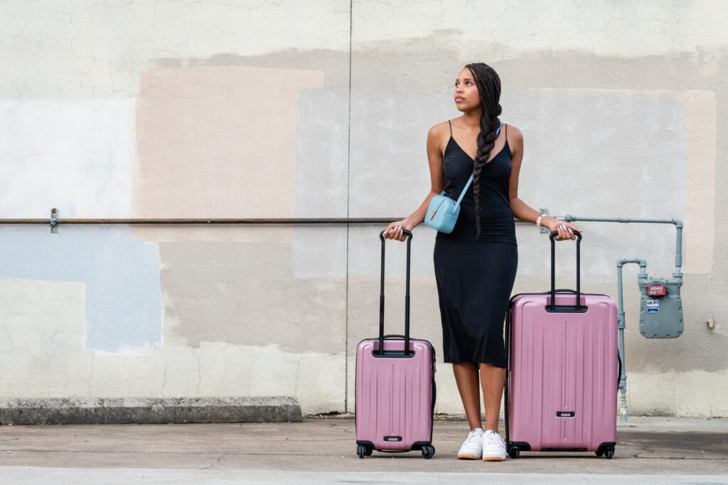 A woman standing next to two suitcases on the street.